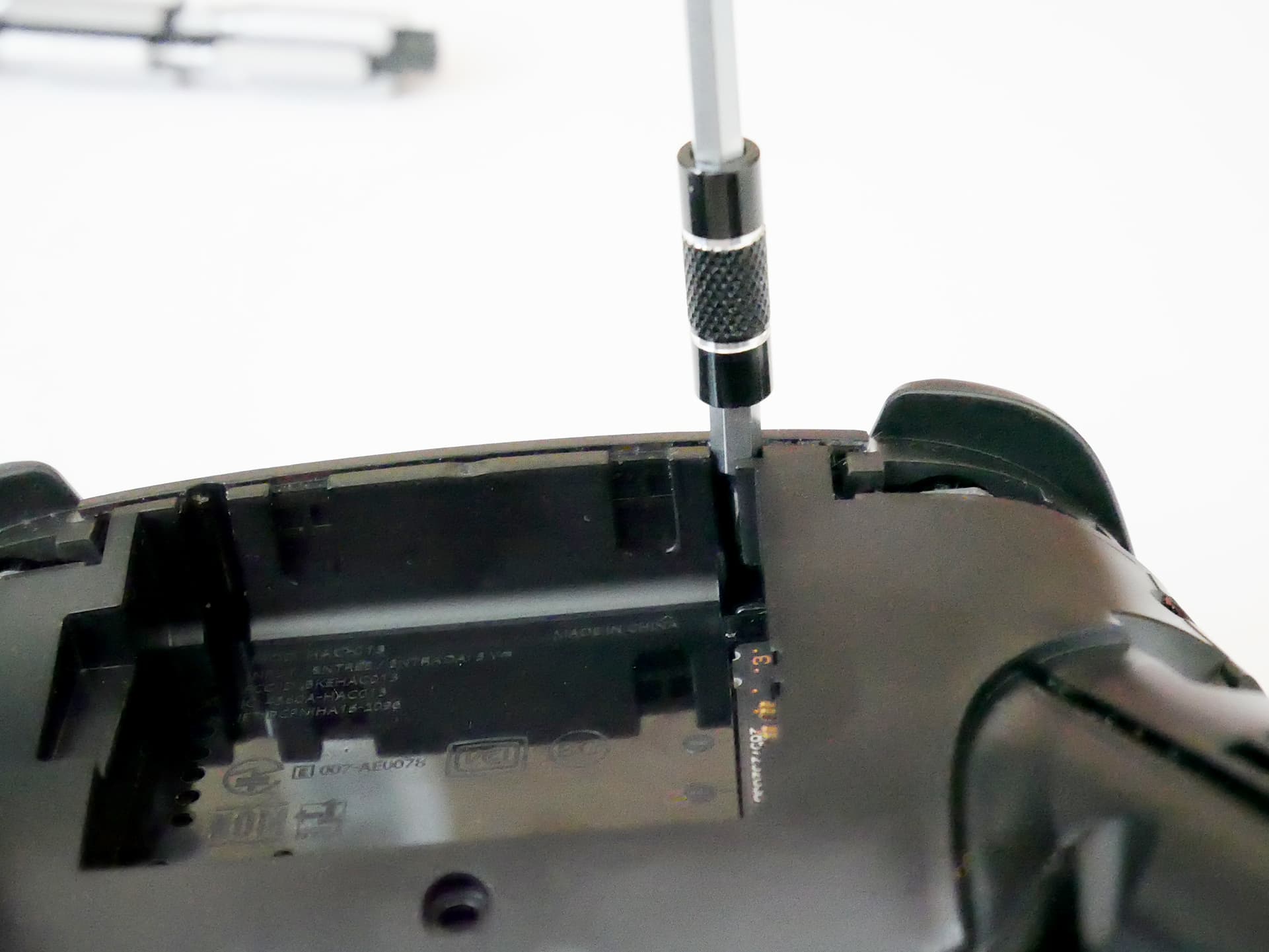 Nintendo Switch のプロコンをペン型電動ドライバーで分解している様子の写真